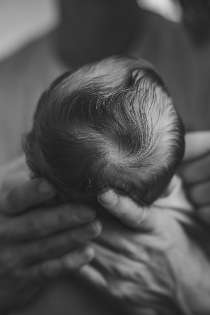 Vater hält Kopf des neugeborenen Babys, Detailaufnahme von den Haaren